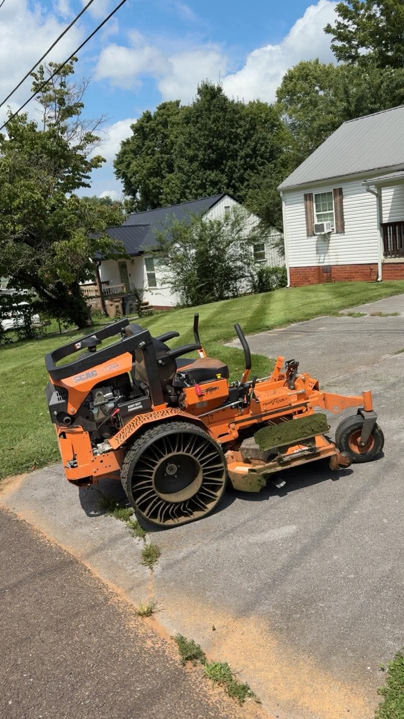 Mike’s orange commercial SCAG mower in front of a freshly striped lawn